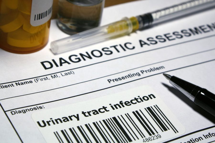 Paper that reads "Diagnostic assessment" and "Diagnosis: Urinary Tract Infection" appears next to a syringe and a pill canister.